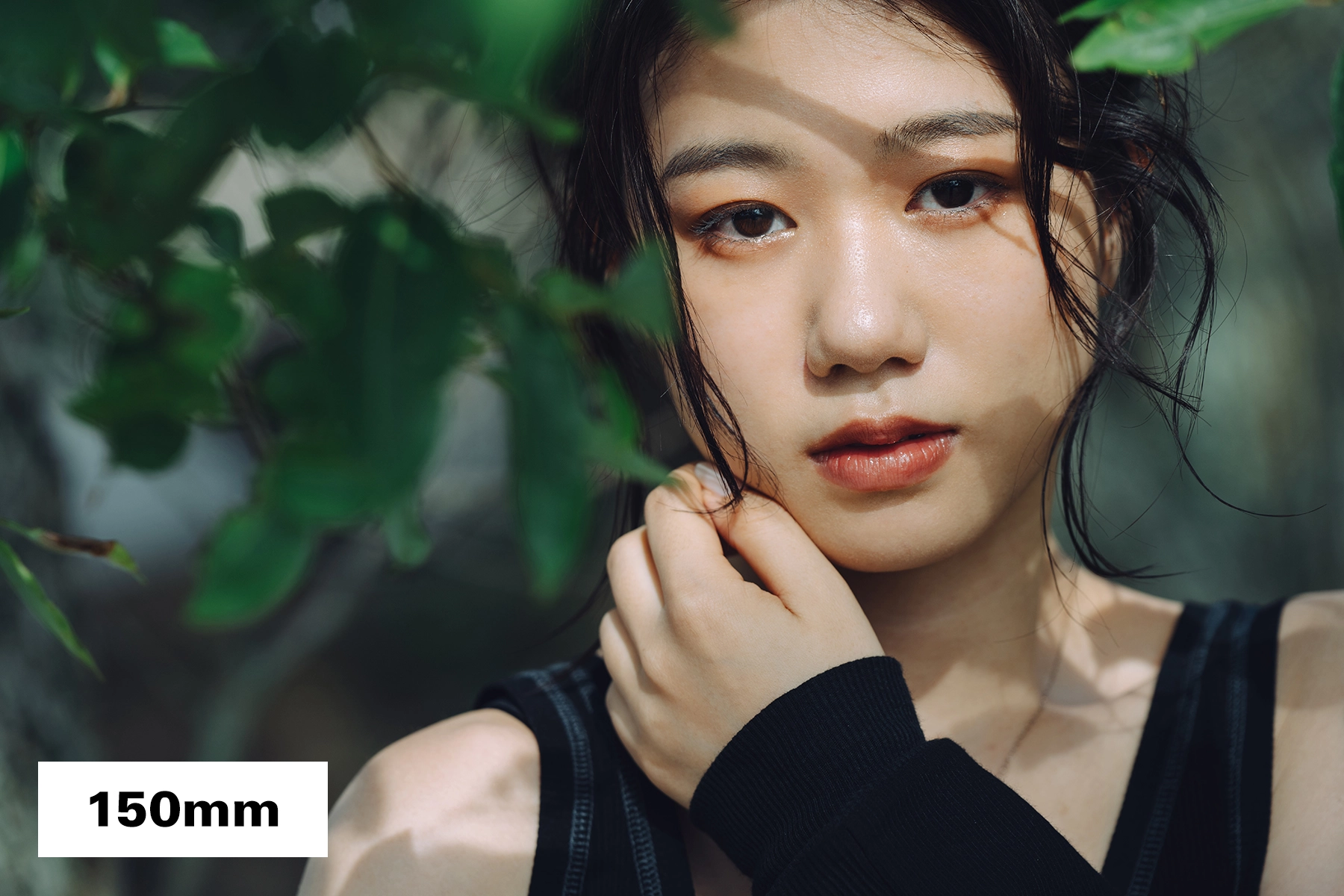 Portrait en gros plan d'une femme photographiée à une longueur focale de 150 mm, mettant en valeur les détails du visage avec une faible profondeur de champ et un arrière-plan doux (bokeh).