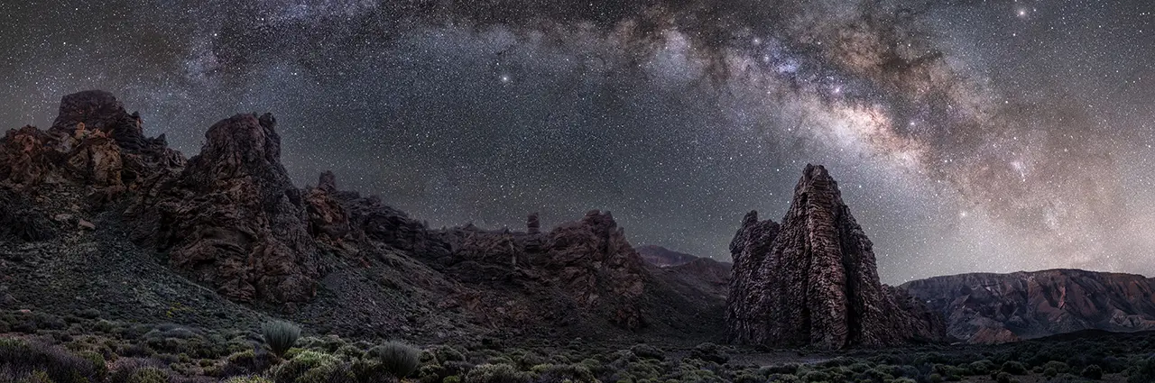 Milky Way stretching across the night sky above rugged rock formations, captured with a Tamron wide-angle f/2.8 lens — showing the detail possible with the best lens for astrophotography and low light scenes.
