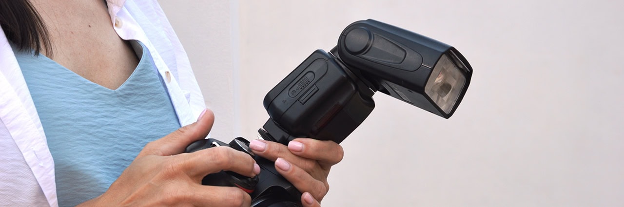 Women holding a camera with an external flash mounted.