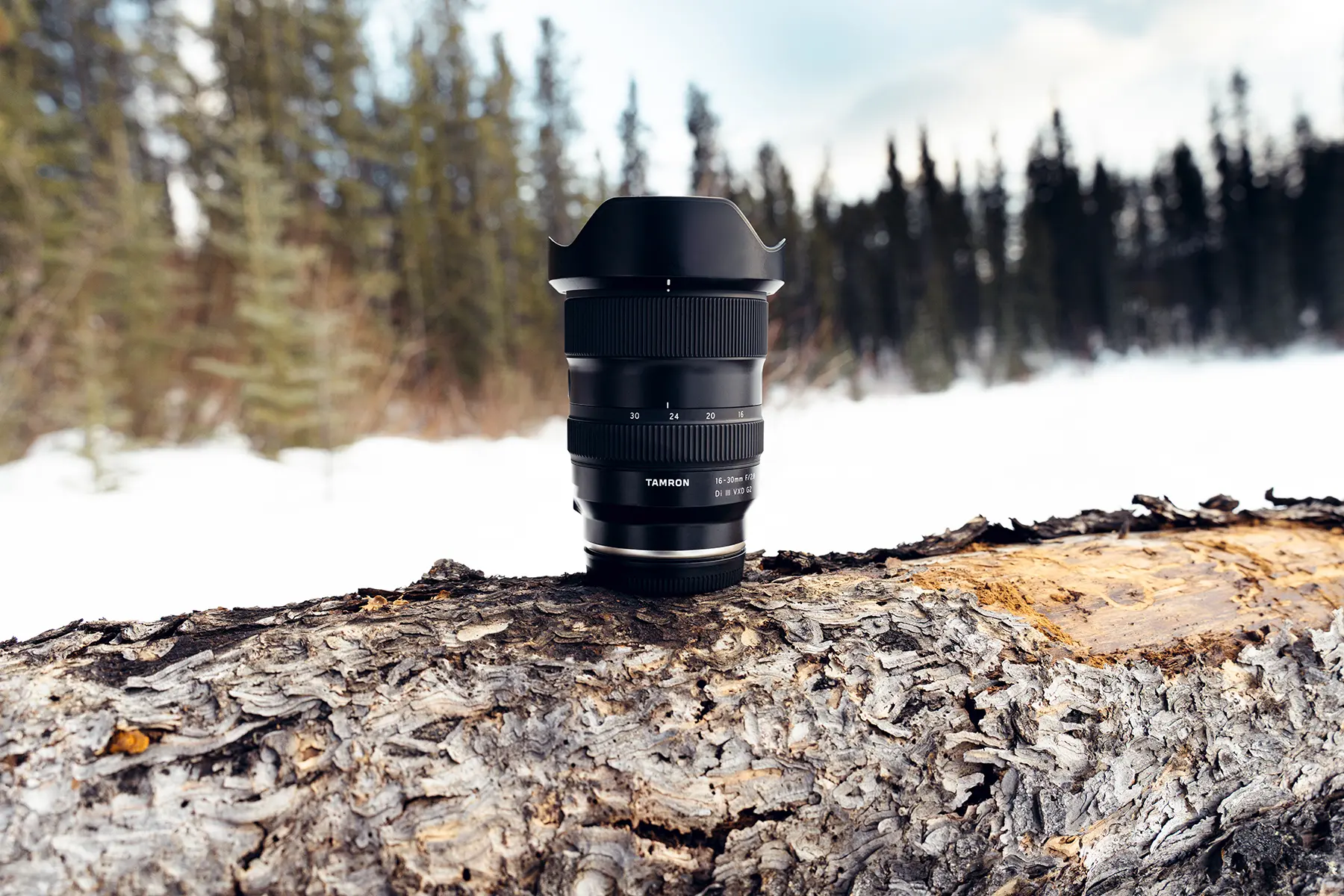 Tamron 16-30mm F2.8 G2 lens standing on a snow-covered log during a Tamron 16-30mm field test in the Yukon, highlighting its rugged design and outdoor durability.