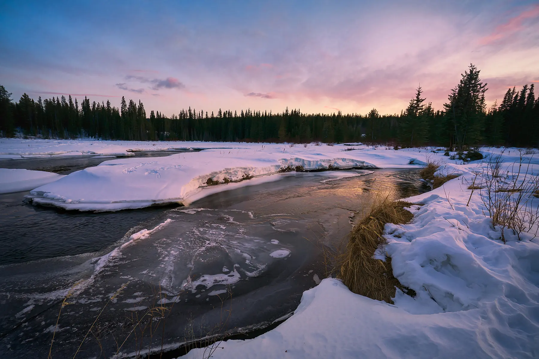 A frozen river winds through a snow-covered landscape at sunset during the Tamron 16-30mm field test, illustrating the lens&rsquo;s ability to capture fine textures, tonal gradients, and natural winter detail across the frame.