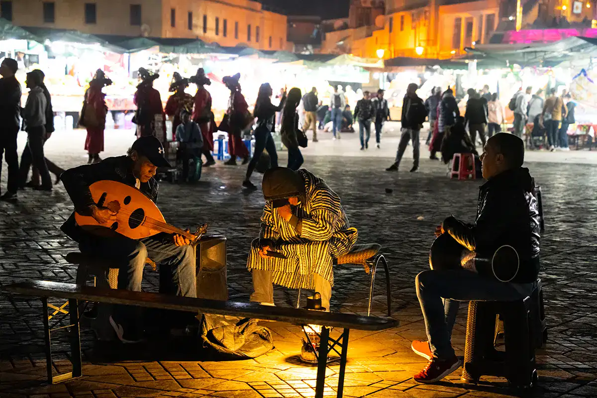 Street musicians performing at night in a lively market square, an atmospheric scene captured with the best lens for street photography.