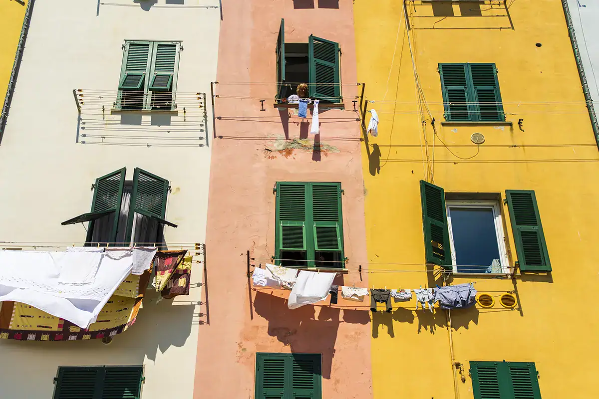 Open green shutters on a pastel wall with clotheslines, highlighting urban detail for the best lens for street photography.