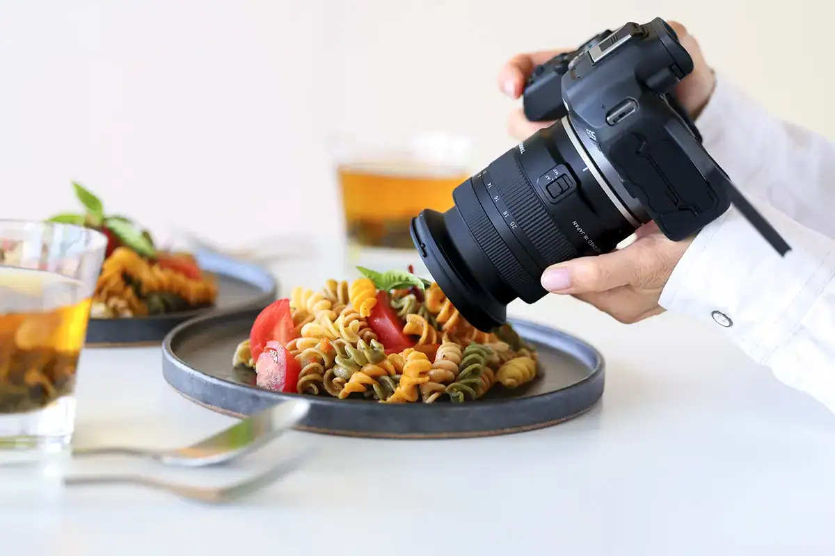 Canon EOS mirrorless camera with Tamron 11-20mm RF mount lens photographing a plate of pasta for food photography.