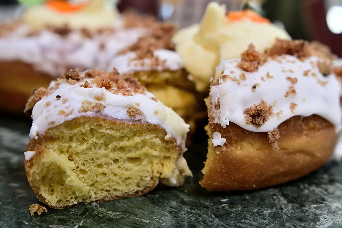 Close-up de donuts gelados de outono com cobertura esfarelada, dispostos em uma superfície rústica para fotografia de alimentos e bebidas de outono.