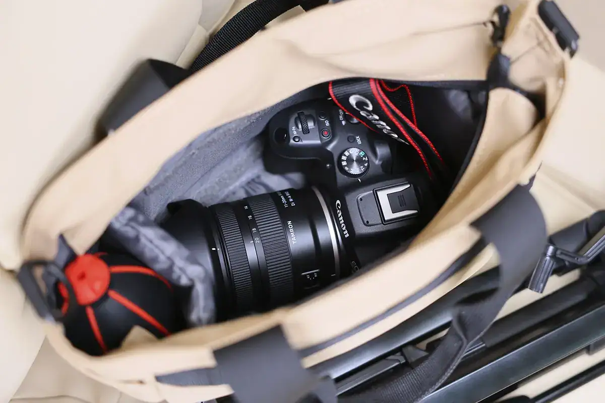 Canon EOS R mirrorless camera with Tamron 11-20mm RF mount lens stored inside a beige camera bag, ready for travel photography.
