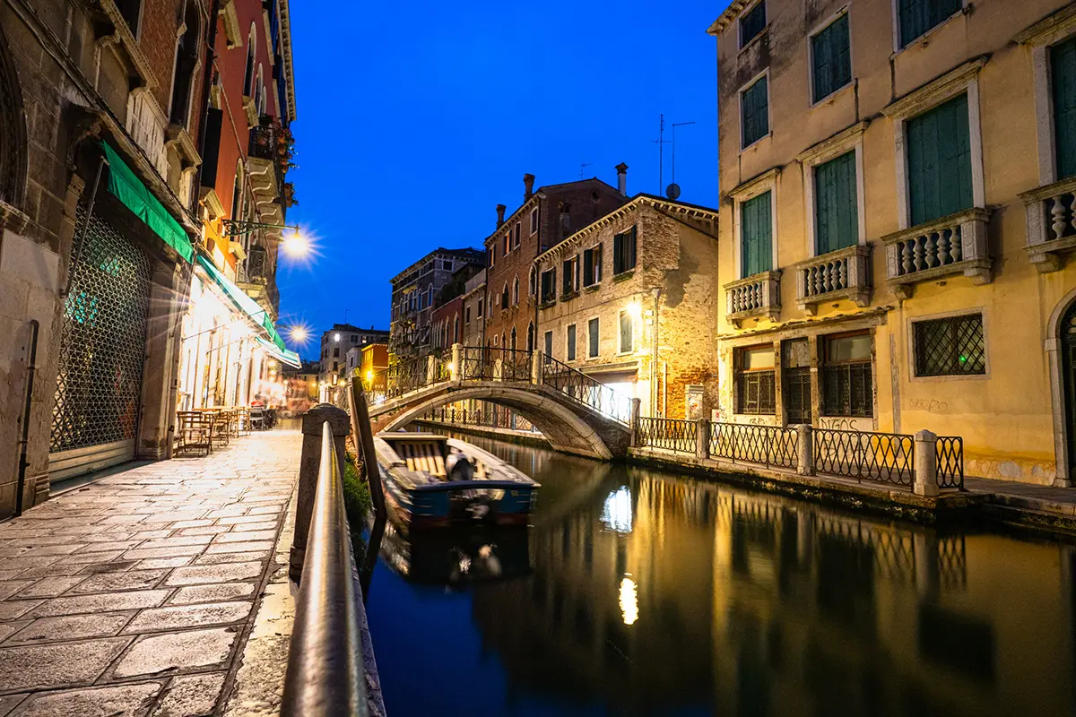 Blue hour photography of a Venetian canal with reflections and a stone bridge, captured for this Venice travel photography guide.