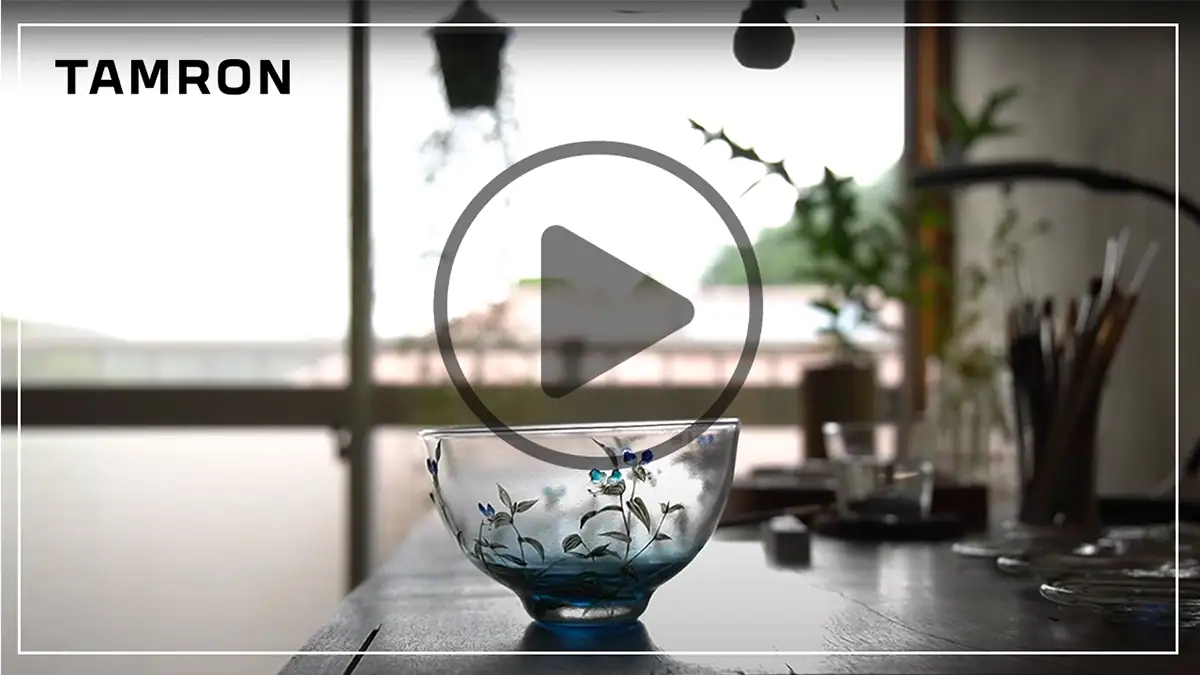 Thumbnail for video that demonstrates focus breathing when shooting video with a mirrorless camera using a glass bowl on a tabletop in a softly lit studio as the subject.