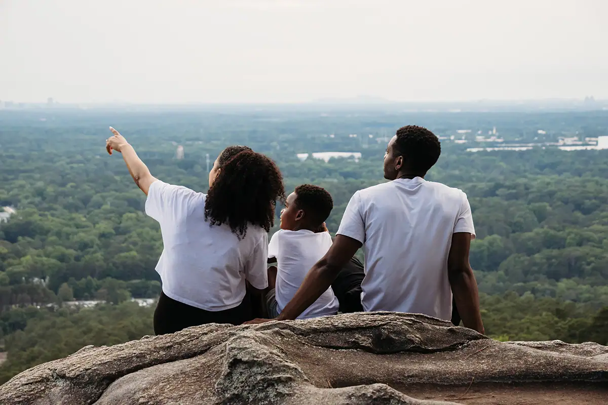 Family sitting on a rock ledge overlooking a scenic landscape during an outdoor family photography session.