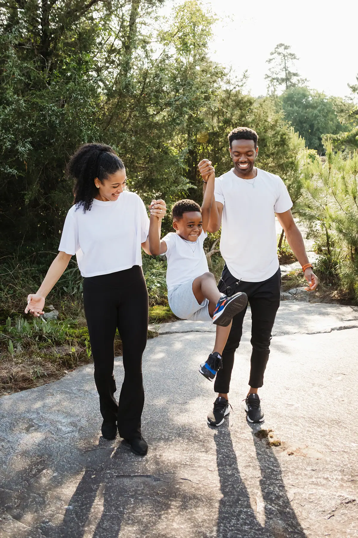 Parents swinging their child while walking outdoors during a candid family photography session.