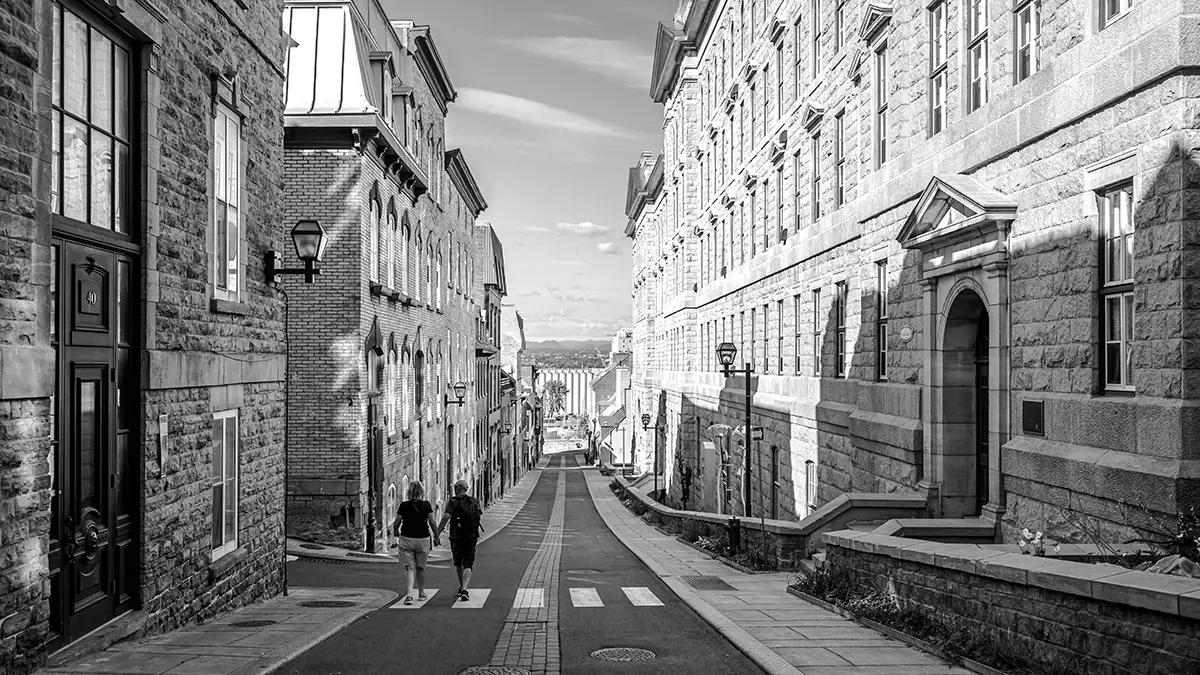 Black and white city street scene photographed with the Tamron 16-30mm F/2.8 Di III VXD G2 wide angle lens, showcasing its strength for travel and architecture photography with sharp lines and depth.