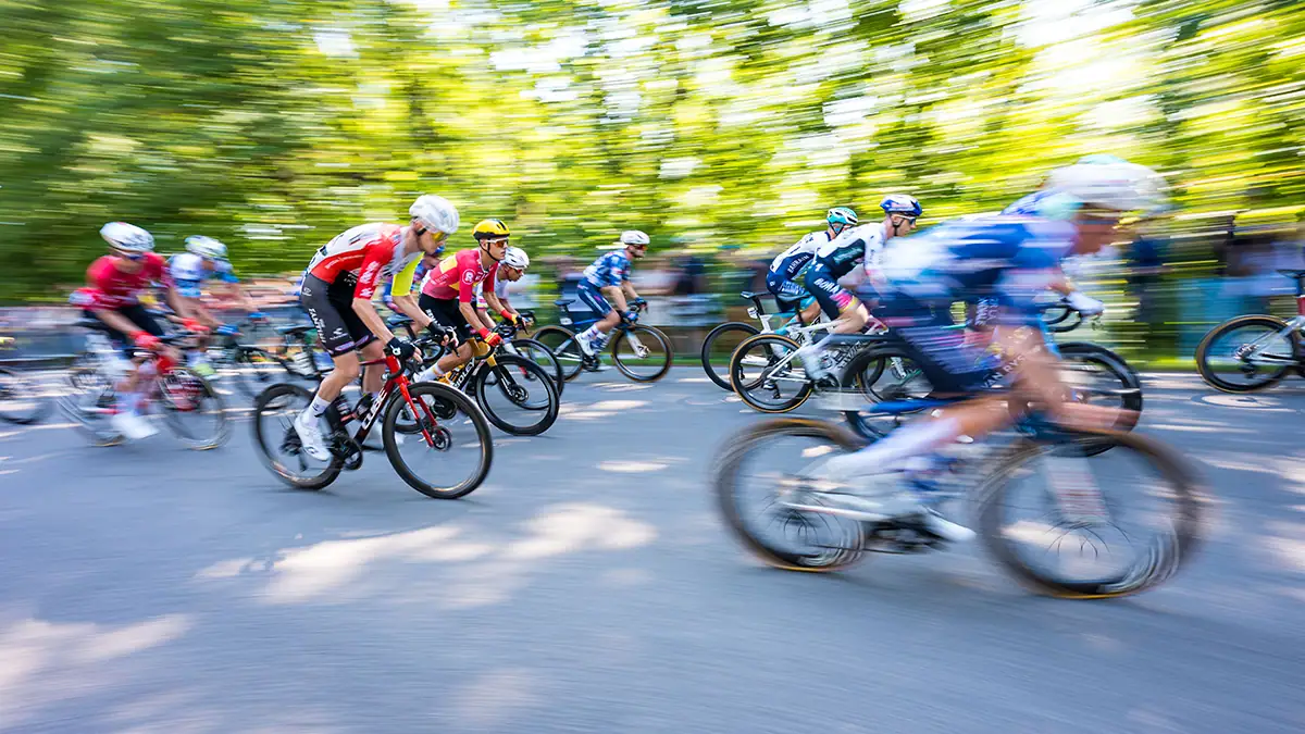 Cyclists in motion during a Grand Prix race, photographed with the Tamron 16-30mm F/2.8 Di III VXD G2 wide angle zoom lens, capturing speed and energy with creative motion blur.