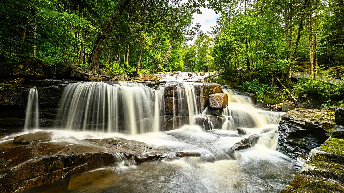 Forest waterfall photographed with the Tamron 16-30mm F/2.8 Di III VXD G2, using a wide angle lens and ND filter to capture motion blur, ideal for landscape photography and travel scenes.