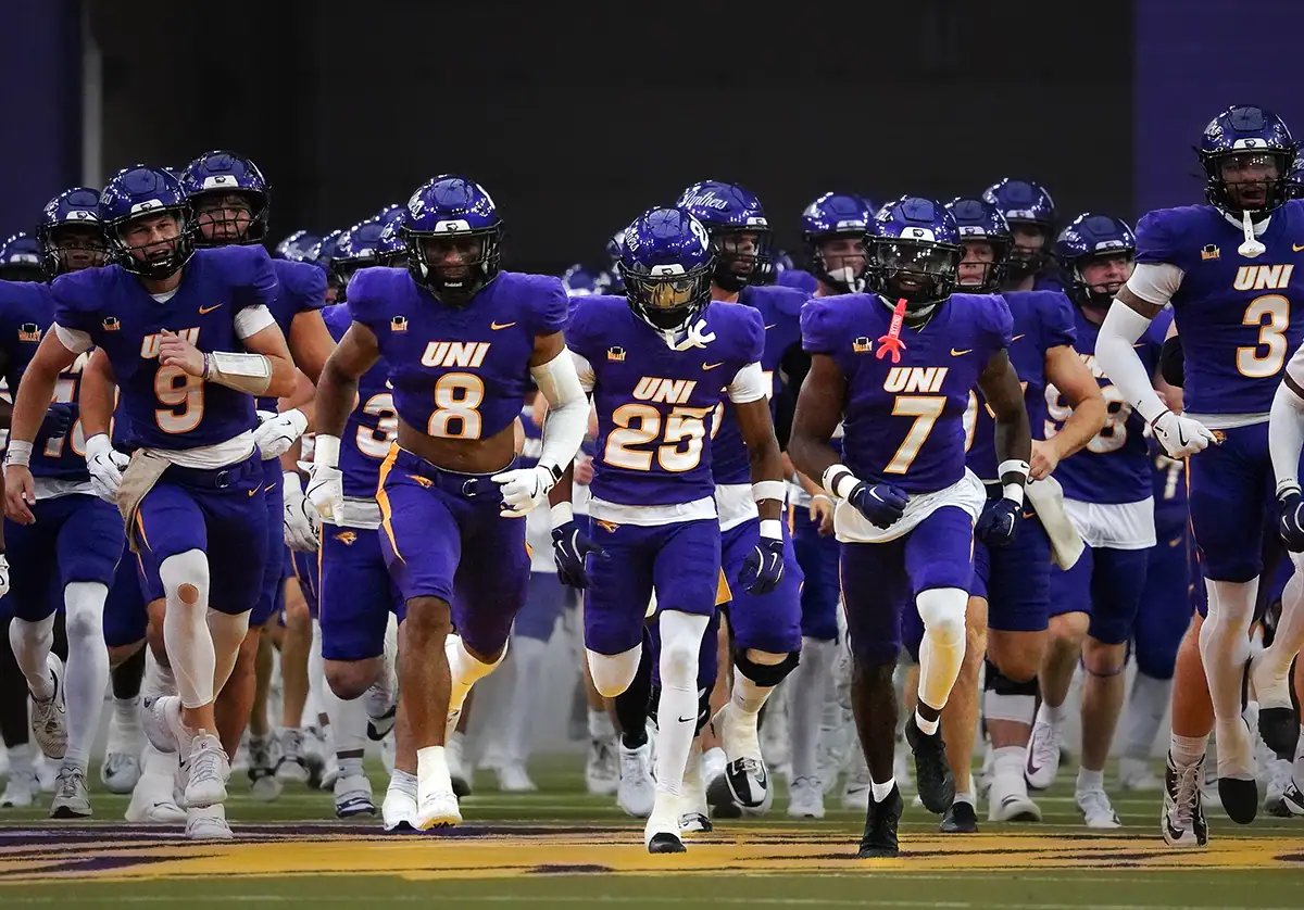 A team of football players running out on the field before the game.