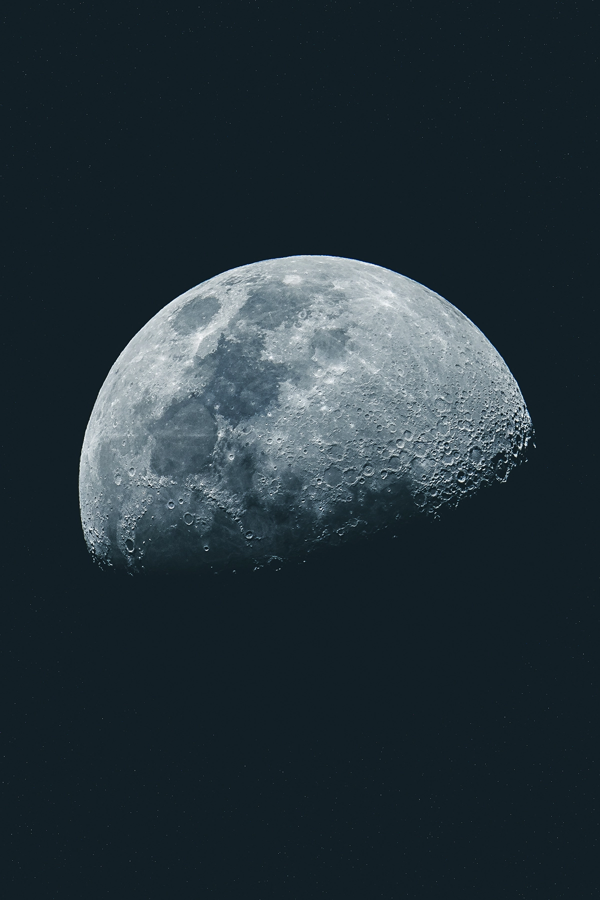 Photograph of a half-moon shot with a telephoto lens showing craters and surface detail.