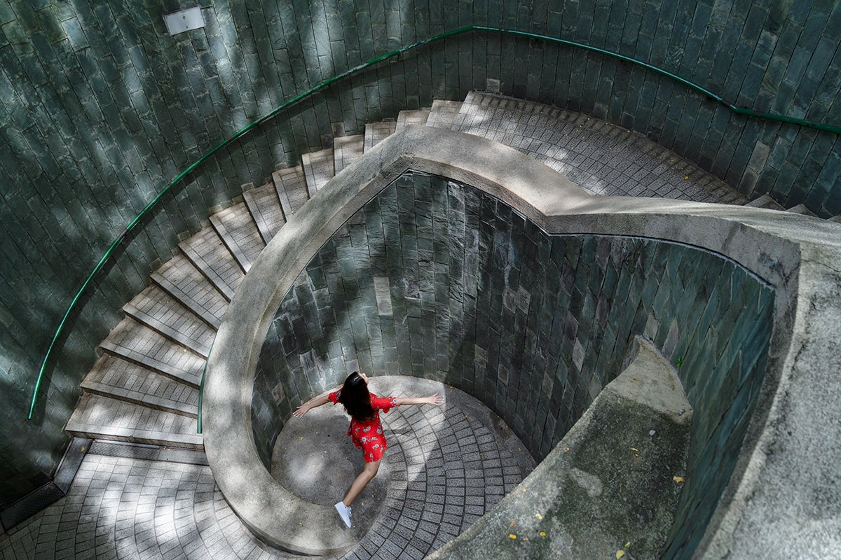 Spiral staircase photographed from above with a woman in red in the power point of the composition, demonstrating the golden ratio and Fibonacci spiral in photo composition.