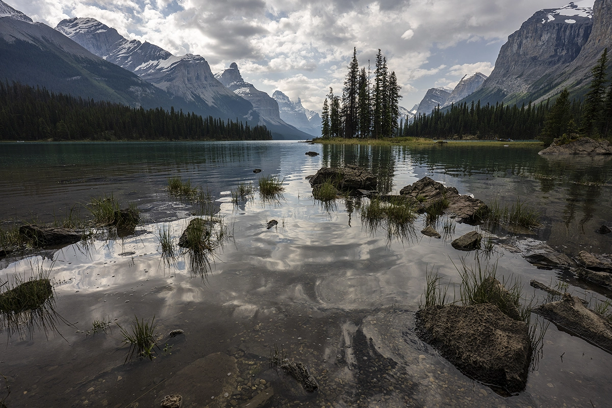 Mountain lake with rocks, grass, trees, and distant peaks, demonstrating the photo composition technique of layering.