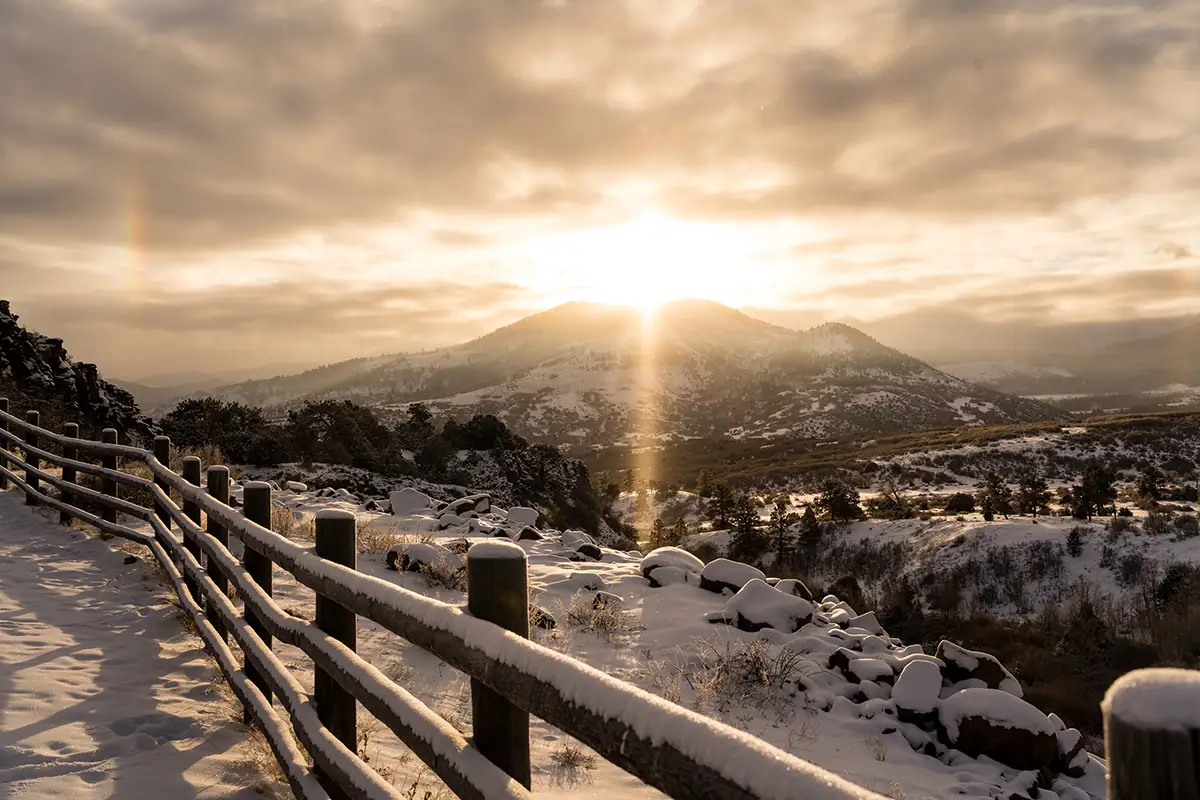 Une image sereine au lever du soleil d'une clôture menant vers des sommets enneigés près de Ridgway.