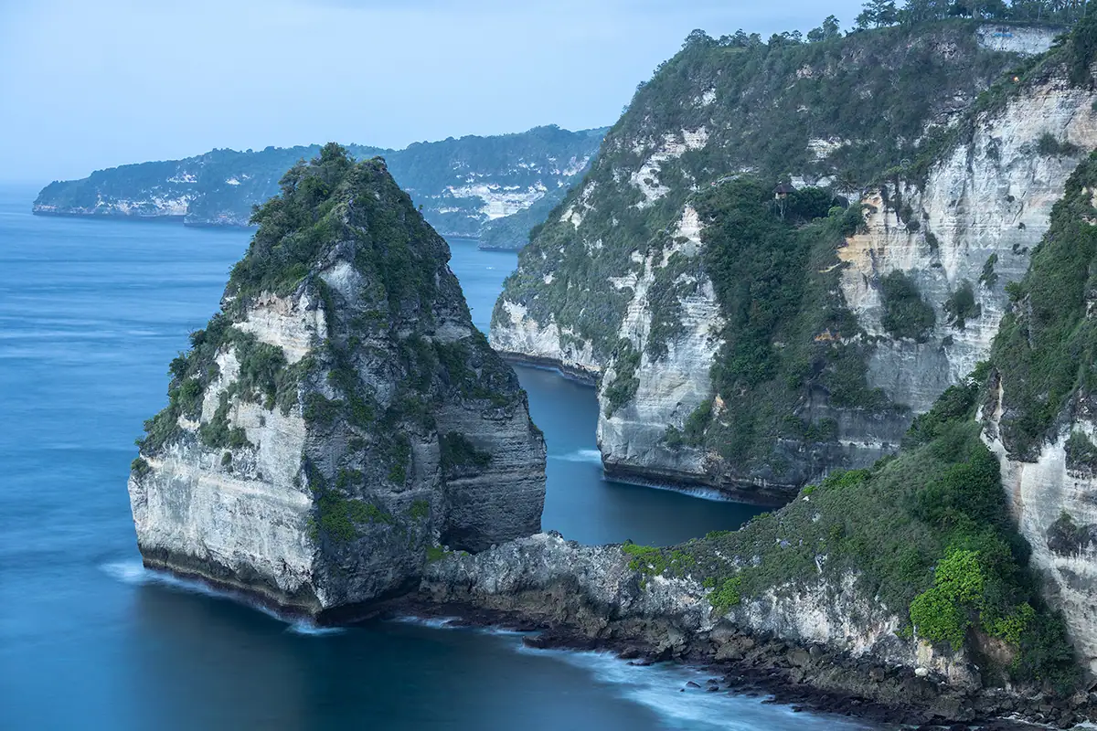 Dramatic limestone sea cliffs and blue ocean along the Indonesian coastline, photographed during travel landscape photography with the Tamron 70-180mm F2.8 G2 lens.