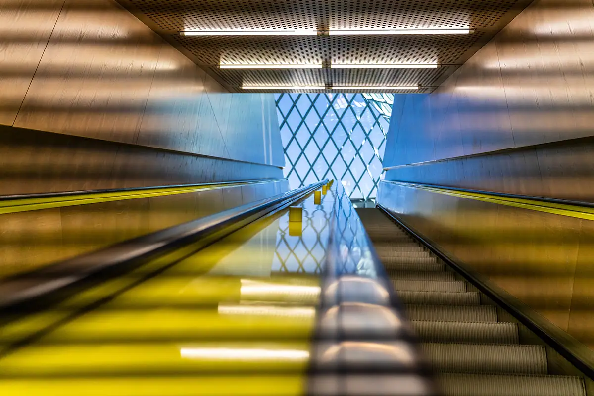Vue abstraite vers le haut d'un escalator jaune à l'intérieur de la bibliothèque publique de Seattle, capturée avec le Tamron 28-75mm F2.8 G2 lors d'un voyage.