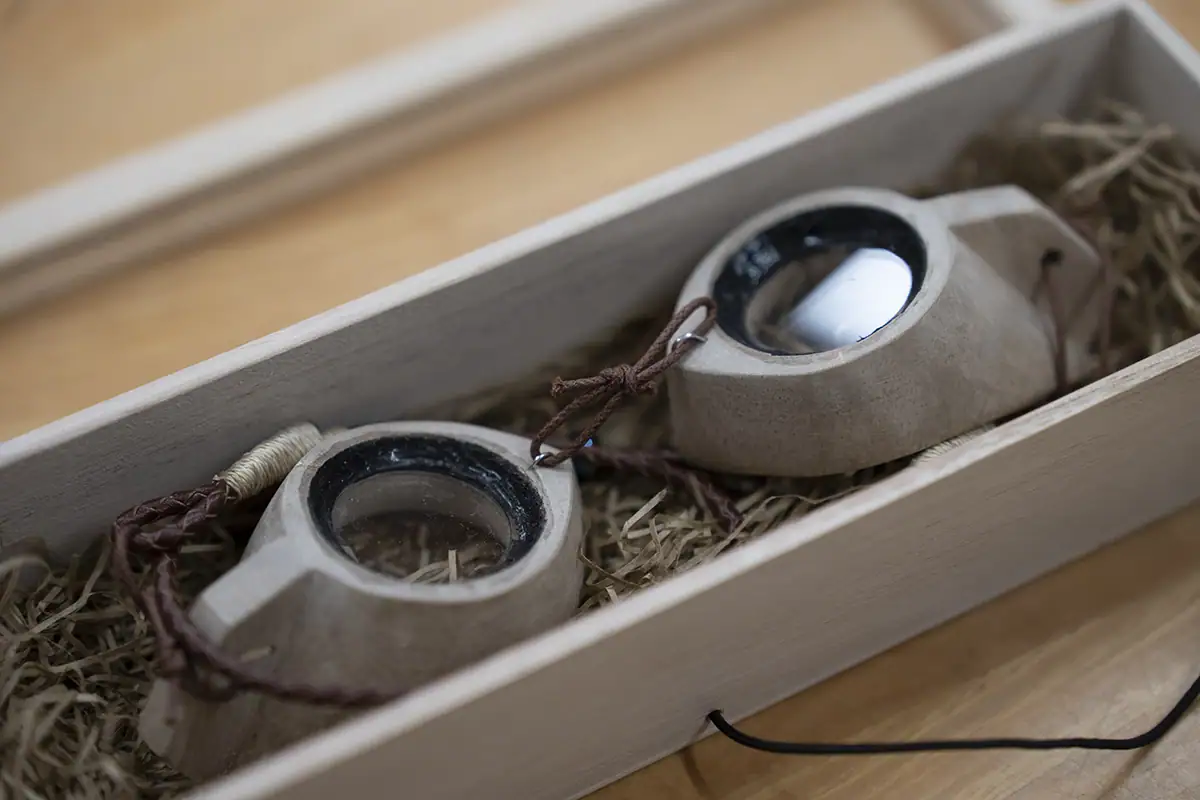 Gros plan sur des lunettes MIIKAGAN fabriquées à la main à Okinawa et reposant dans une boîte en bois, photographiées avec le Tamron 28-75mm F2.8 G2 pour mettre en valeur l'artisanat culturel dans le cadre d'un documentaire visuel.