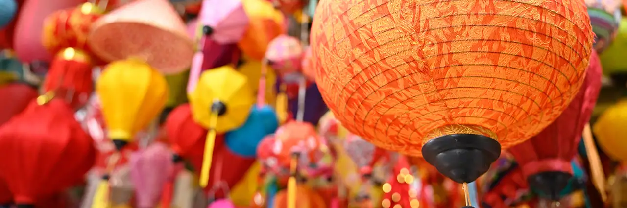 Faroles colgantes de colores en un mercado vietnamita, con un farol naranja brillante en primer plano, fotografiado con el Tamron 28-75 mm F2.8 G2.