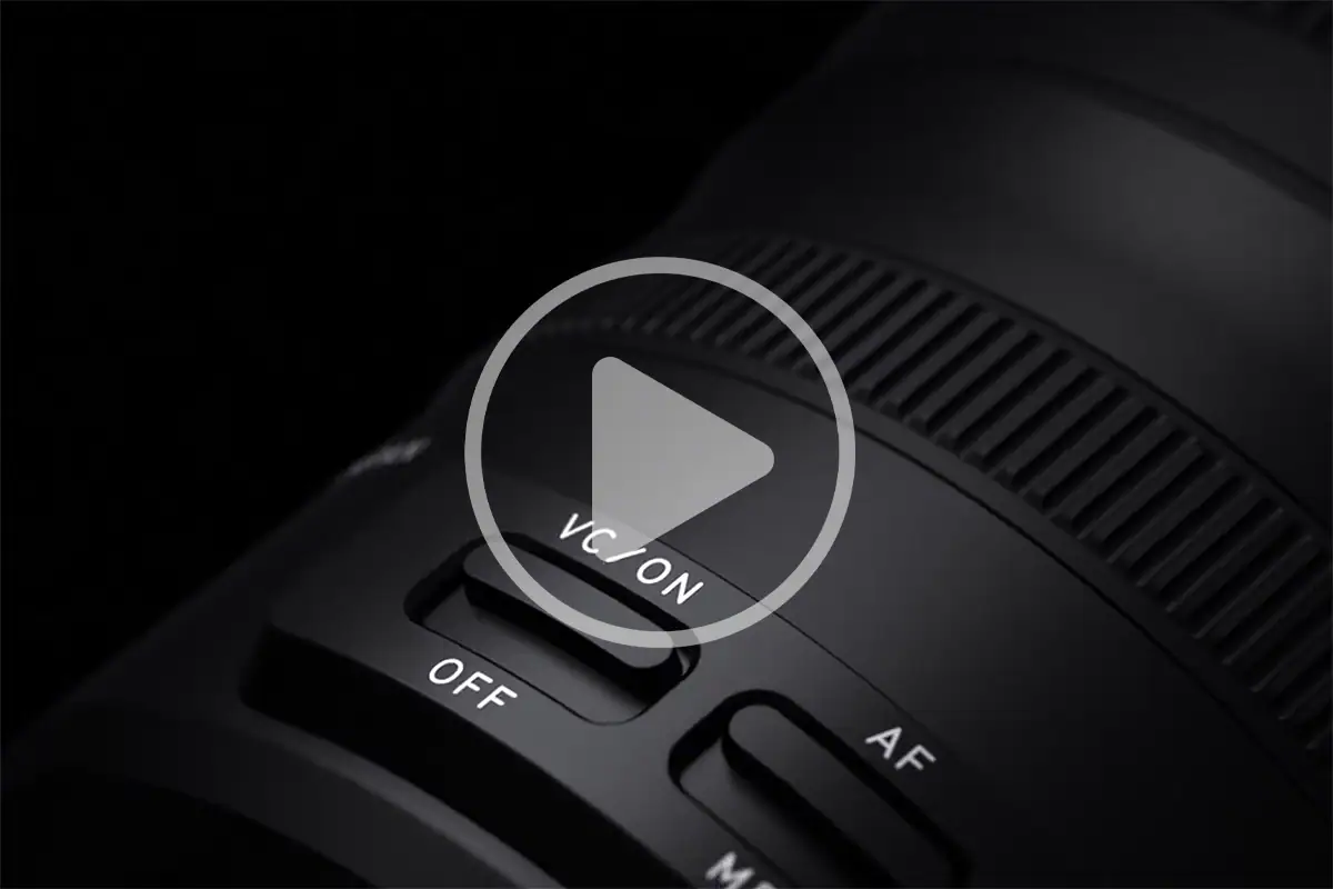 Close-up of a Tamron lens showing the VC vibration compensation switch for optical image stabilization.