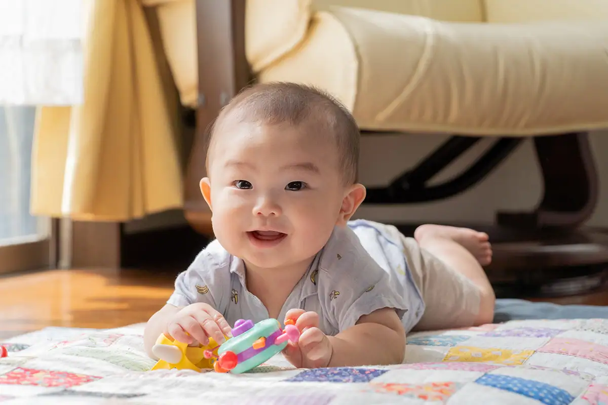 Foto cotidiana de um bebê brincando em um cobertor dentro de casa, ilustrando a versatilidade de uma lente zoom multifuncional.