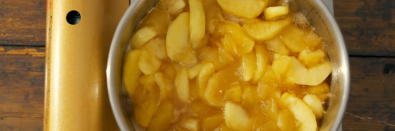 Garniture de tarte aux pommes mijotant dans une casserole, vue de dessus.
