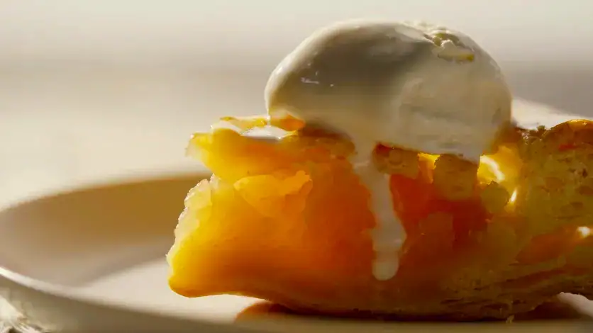 Gros plan sur une tarte aux pommes avec de la crème glacée fondante pour mettre en valeur la texture, la chaleur et une faible profondeur de champ cinématographique.