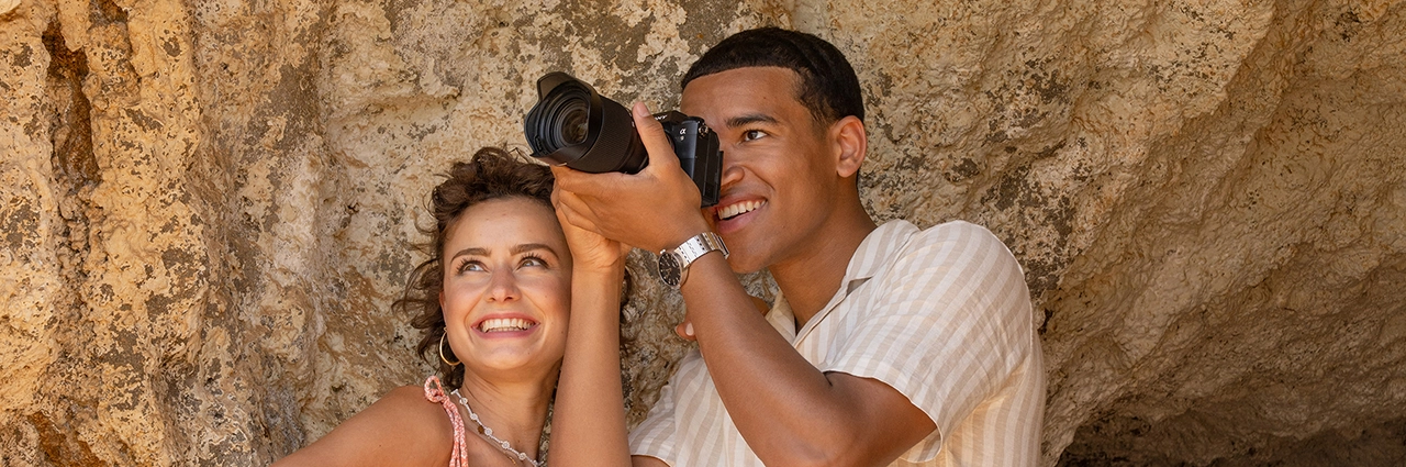 Fotógrafo usando uma câmera e lentes ao ar livre, representando a escolha de lentes para diferentes tipos de fotografia.