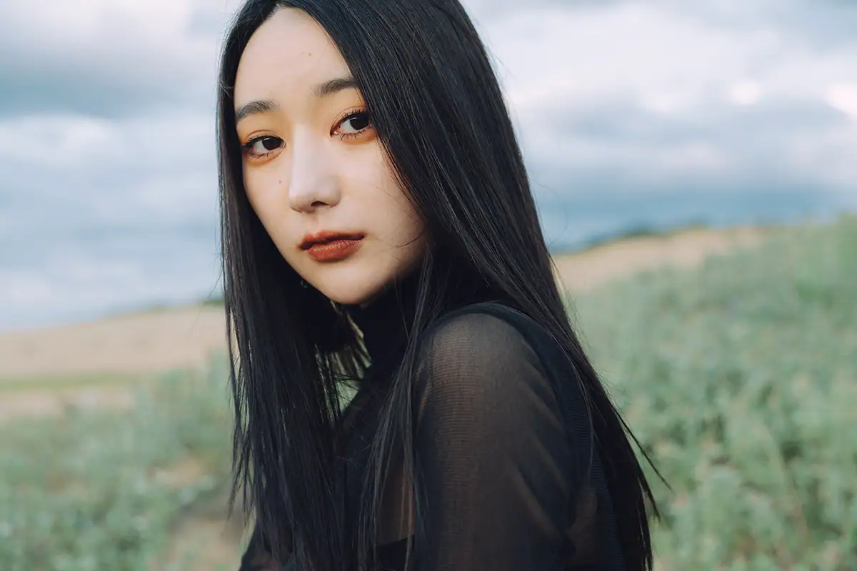 Foto de retrato de uma mulher com um fundo suavemente desfocado, demonstrando o isolamento do tema e a profundidade de campo rasa.