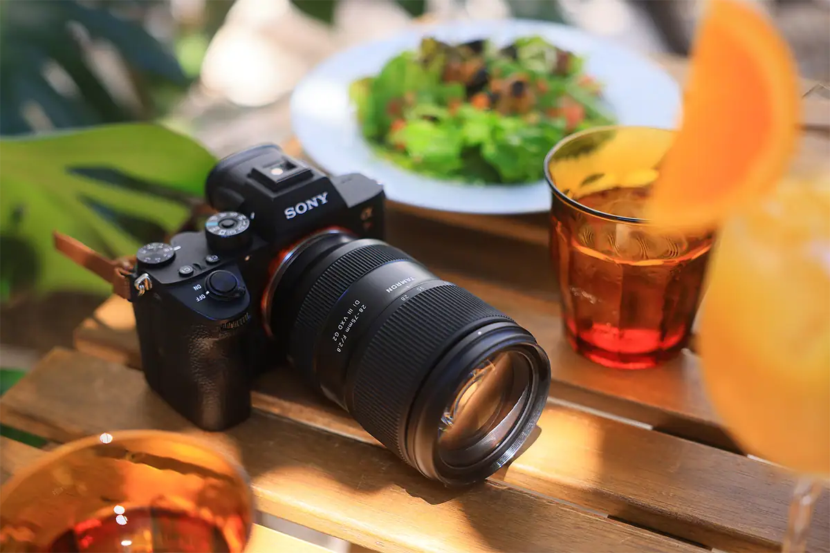 Lente Tamron 28-75 mm F/2.8 Di III VXD G2 (modelo A063) montado en una cámara sin espejo Sony sobre una mesa al aire libre.