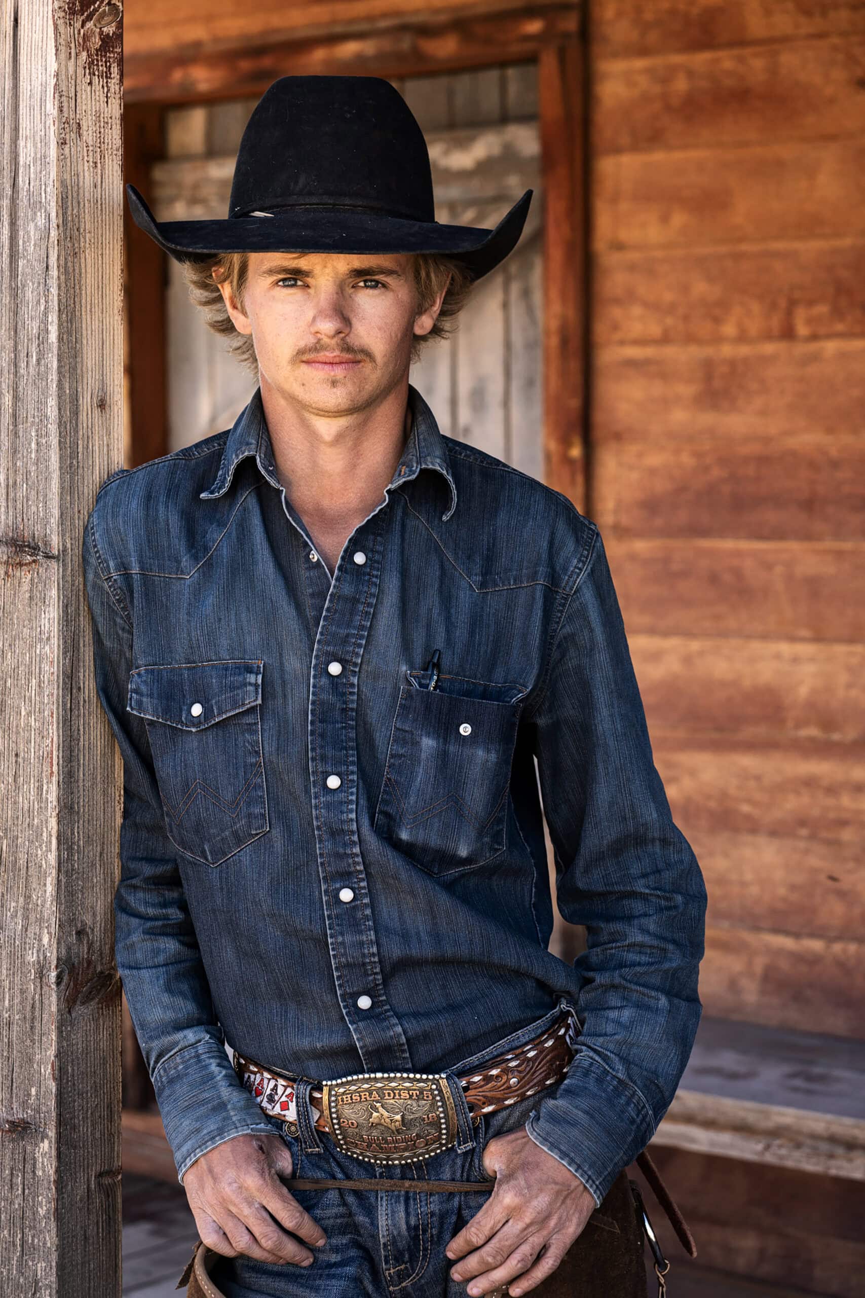 Retrato de caubói usando camisa de brim e chapéu, fotografado com a lente Tamron 35-100 mm F/2.8 Di III VXD.