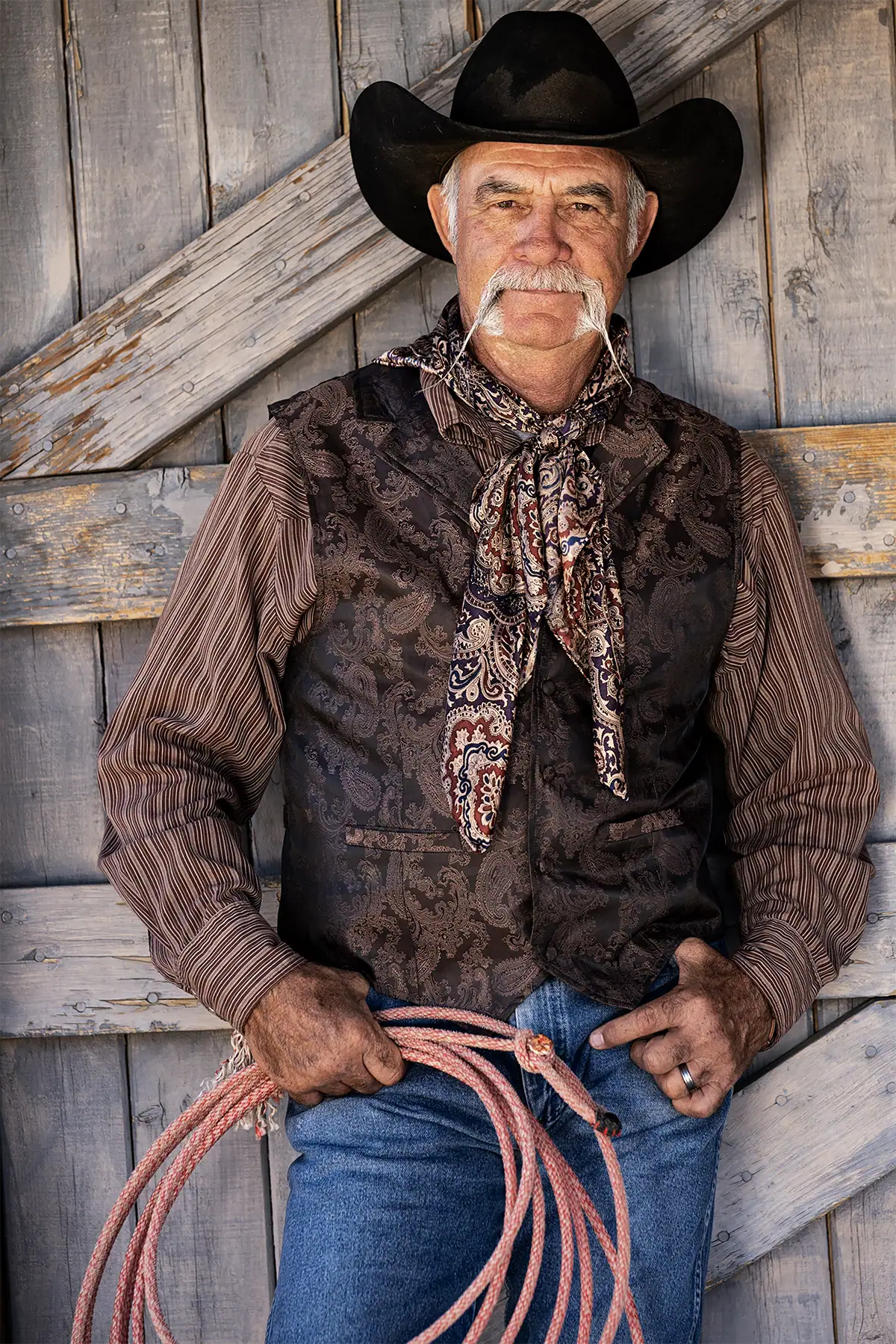 Retrato de caubói segurando uma corda de laço fotografado com a lente Tamron 35-100 mm F/2.8 Di III VXD.