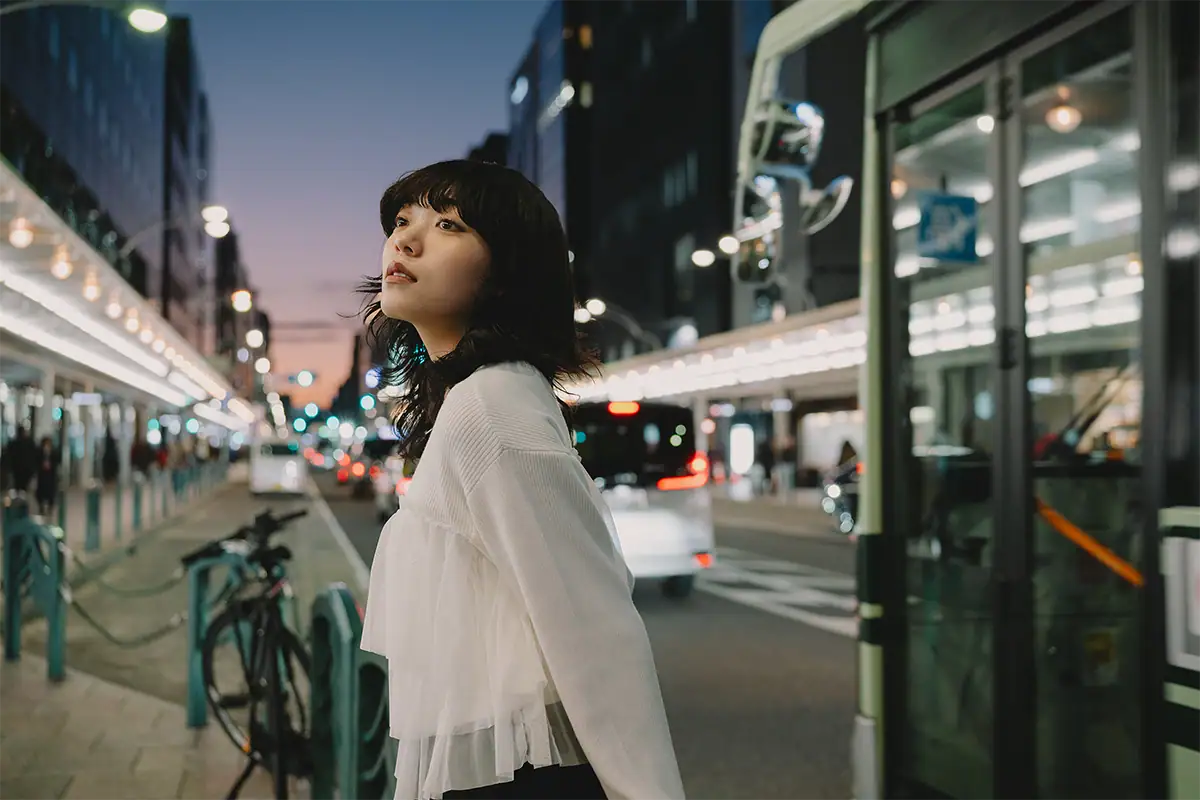 Retrato espontáneo de una mujer mirando hacia arriba en una calle de la ciudad al atardecer.