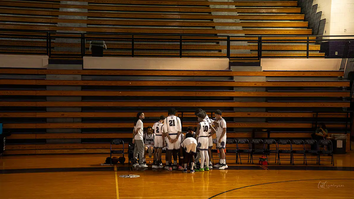 A basketball team on the sidelines talking strategy with the coach