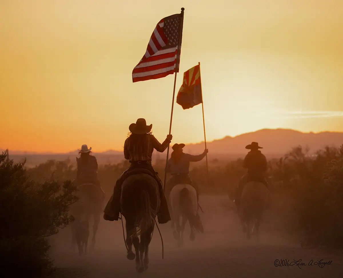 Cowboys montados em cavalos segurando uma bandeira americana e do Arizona.