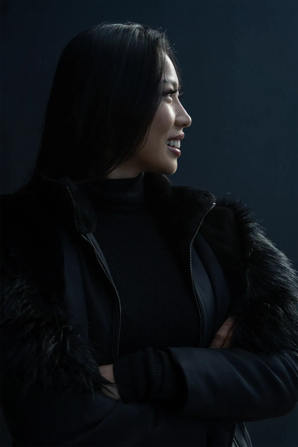 Woman in profile lit with hard directional light and deep shadow for a moody portrait.