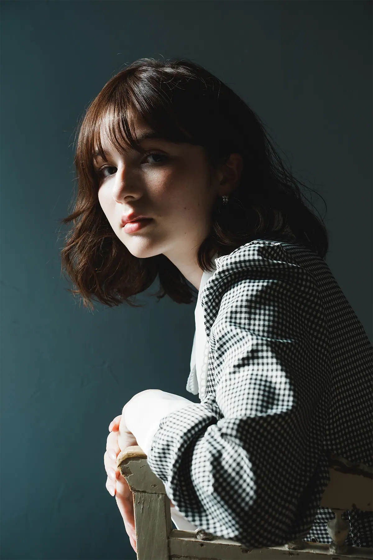 Close portrait of a woman with split-style moody lighting and strong shadow across one side of the face.