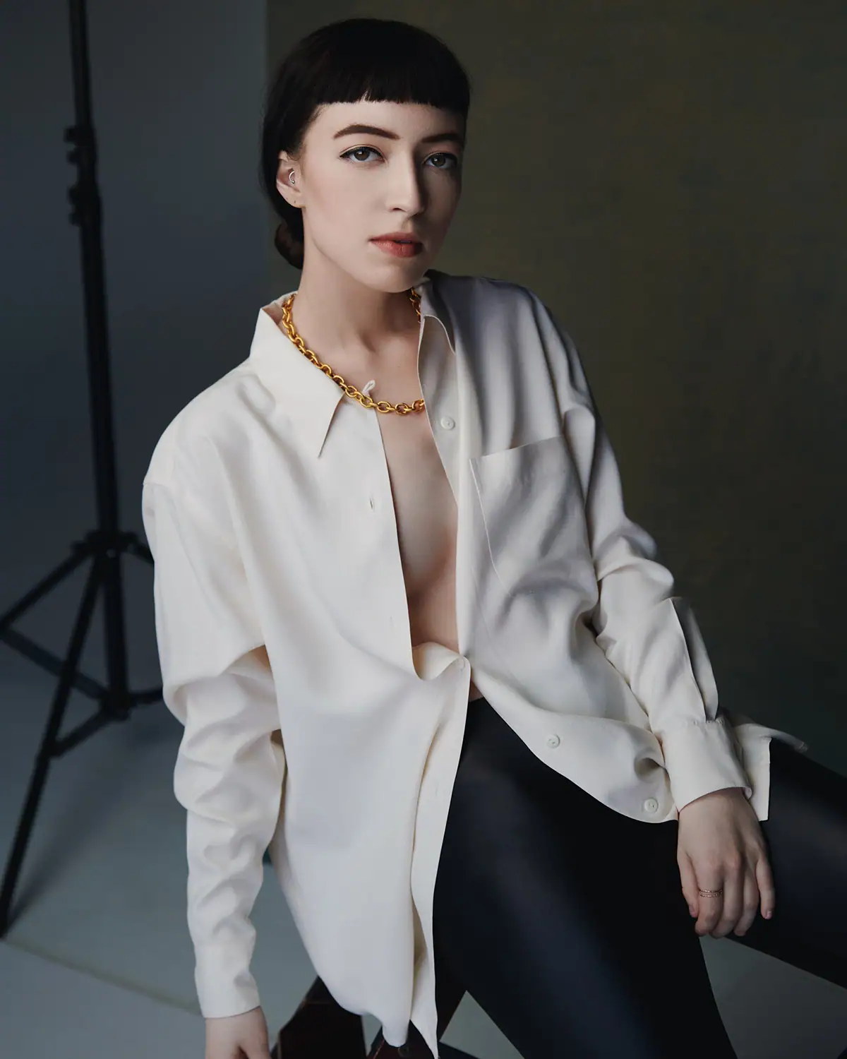 Portrait de studio d'une femme en chemise blanche éclairée par une lumière directionnelle raffinée pour un look de mode soigné.