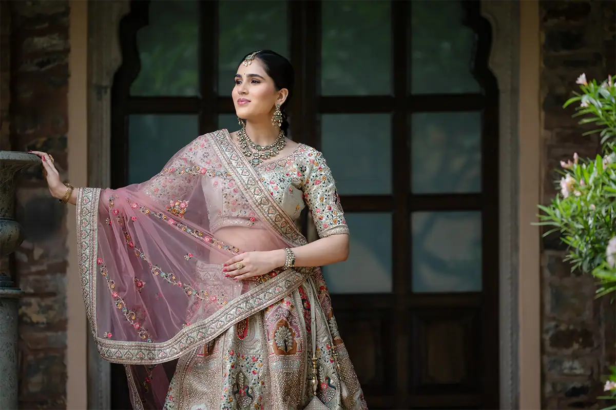 Woman in embroidered formalwear posing in front of an arched doorway for a portrait photograph.