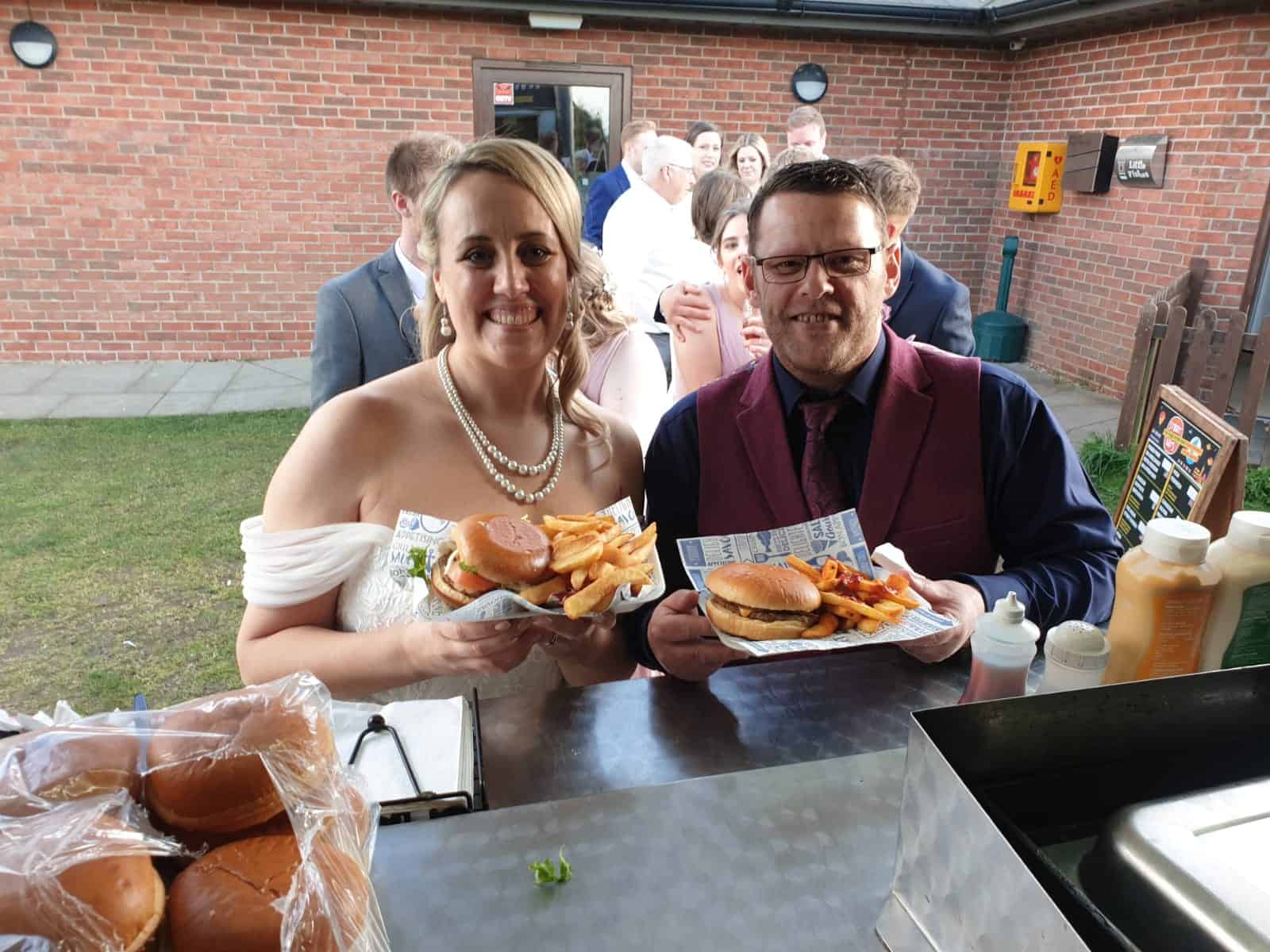 Bride and groom with burgers at their wedding reception from KK Catering burger van