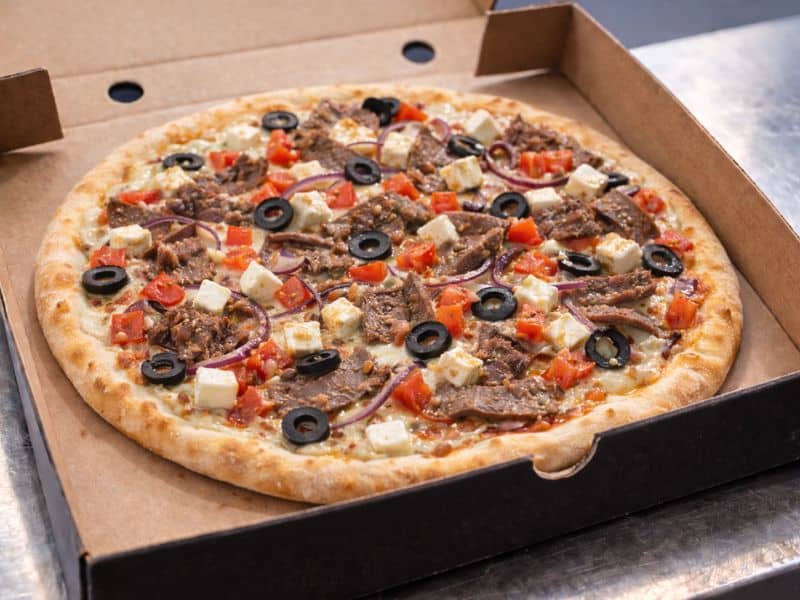 The Greek gourmet pizza with white sauce, kebab meat, tomatoes, onions, olives, feta and mozzarella from KK Catering.