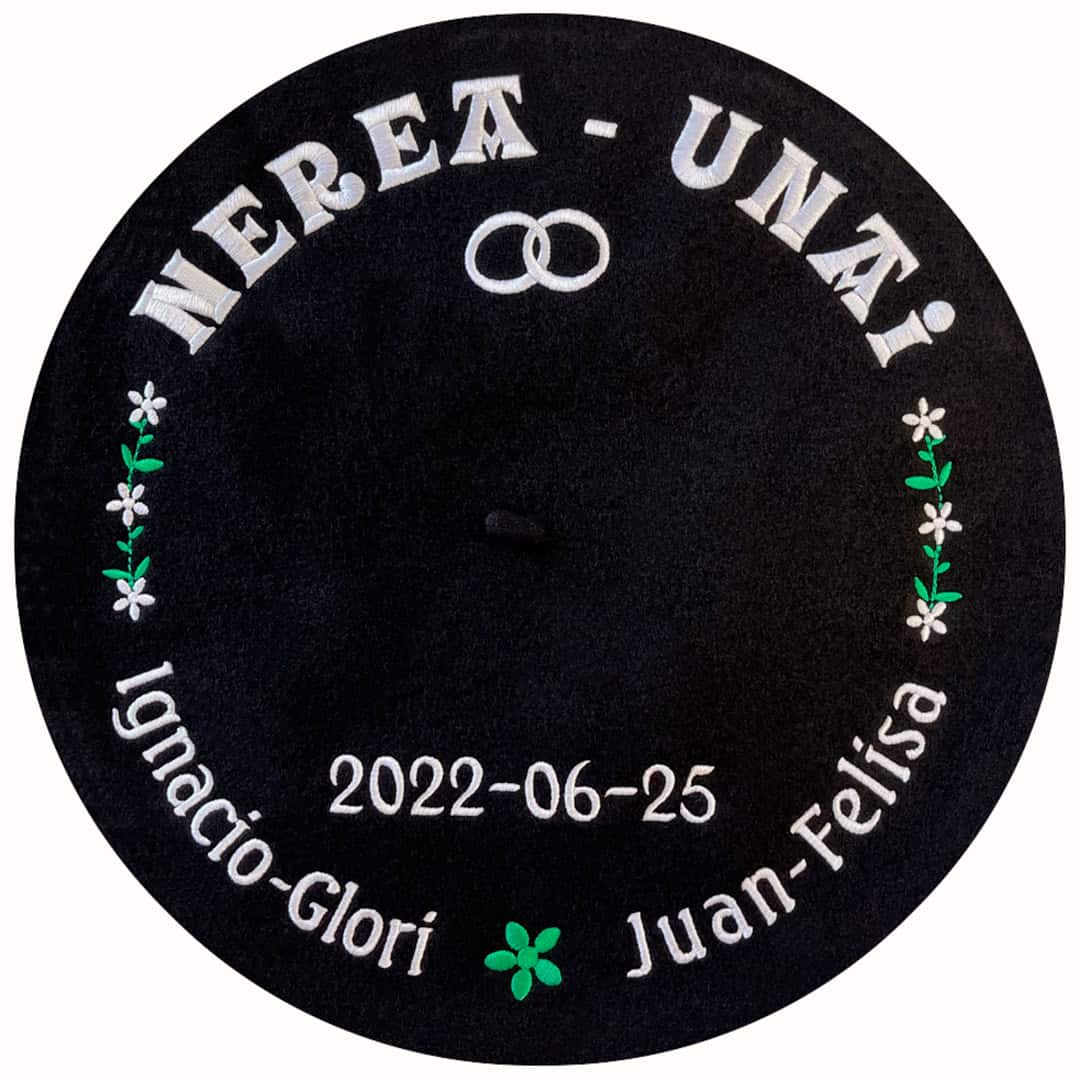 Txapela para boda personalizada con hilo blanco y verde con nombres, lazos de flores y alianzas bordadas