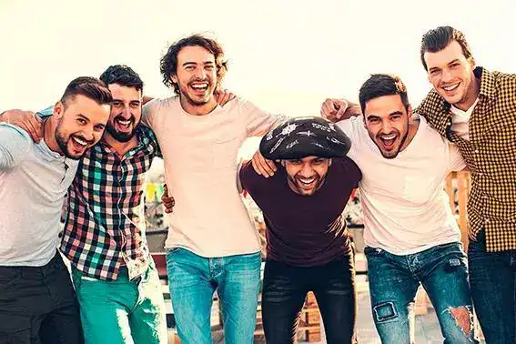 Amigos abrazados celebrando el cumpleaños del que lleva una txapela de regalo