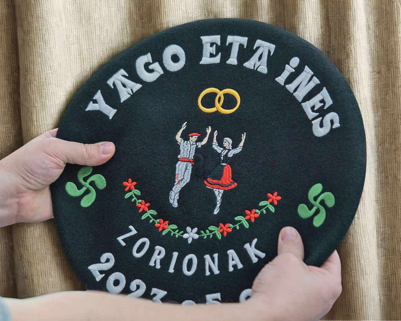 Txapela bordada personalizada con textos en arco, símbolos vascos e imágenes distribuidas de forma equilibrada sobre el paño circular