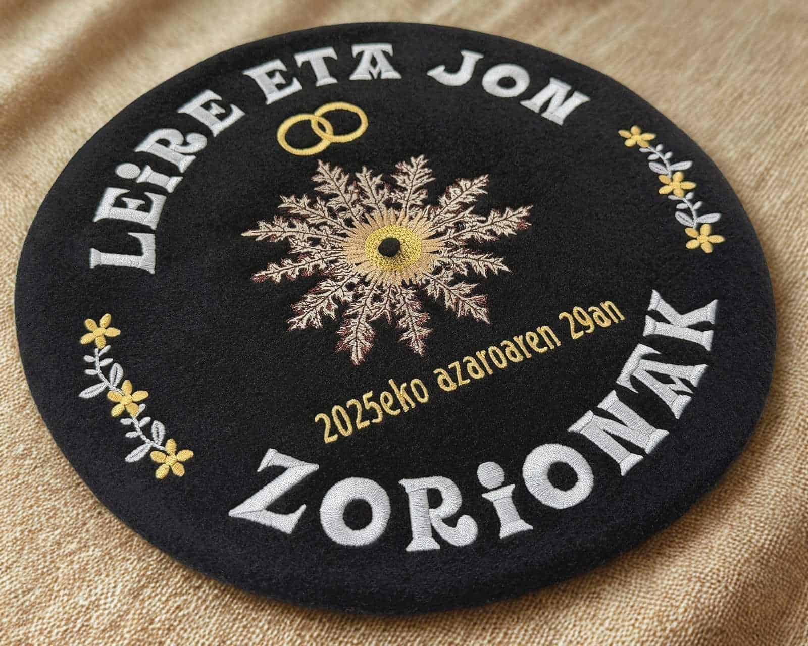Txapela bordada para boda con textos en blanco, alianzas doradas y eguzkilore, ejemplo de paleta ordenada y lectura clara en Teletxapela.