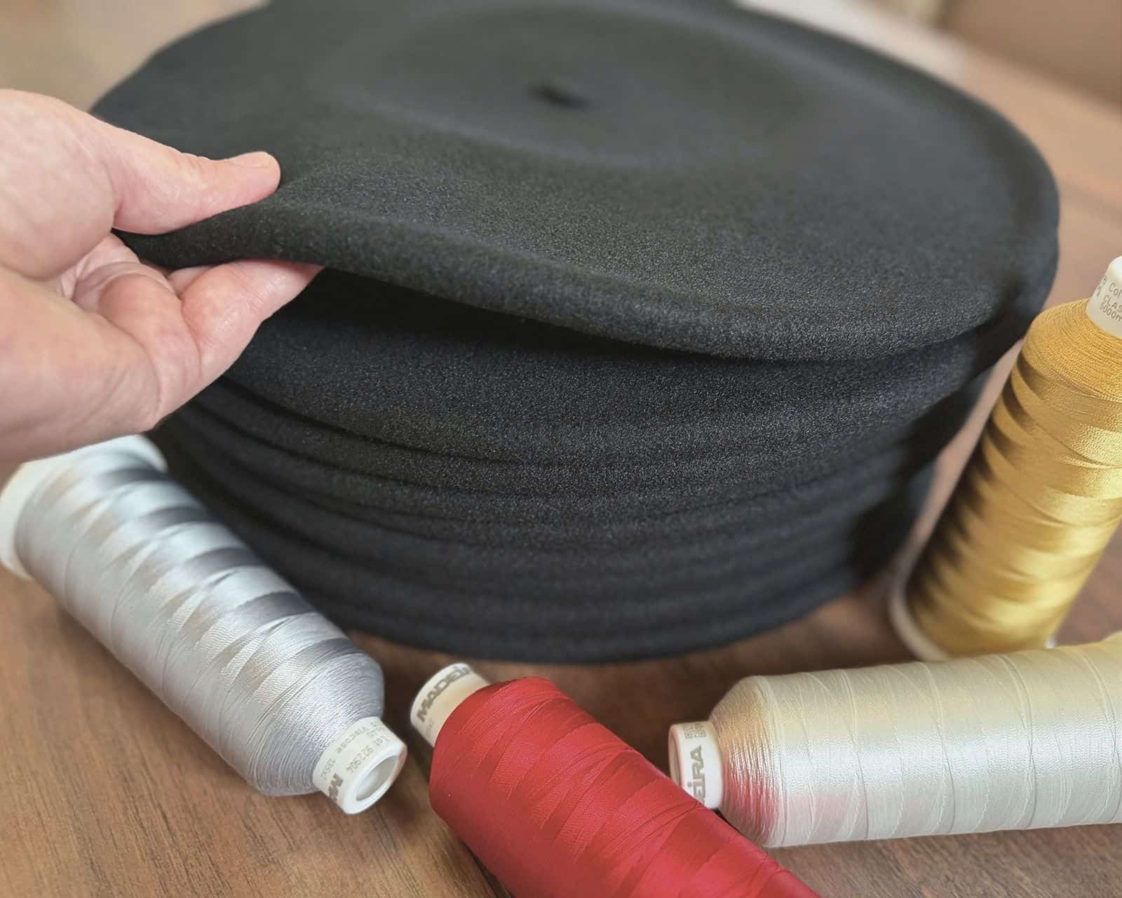 Paños de txapela apilados con hilos de bordado, mostrando el cuerpo del paño y la base material de una txapela bordada de calidad en Teletxapela