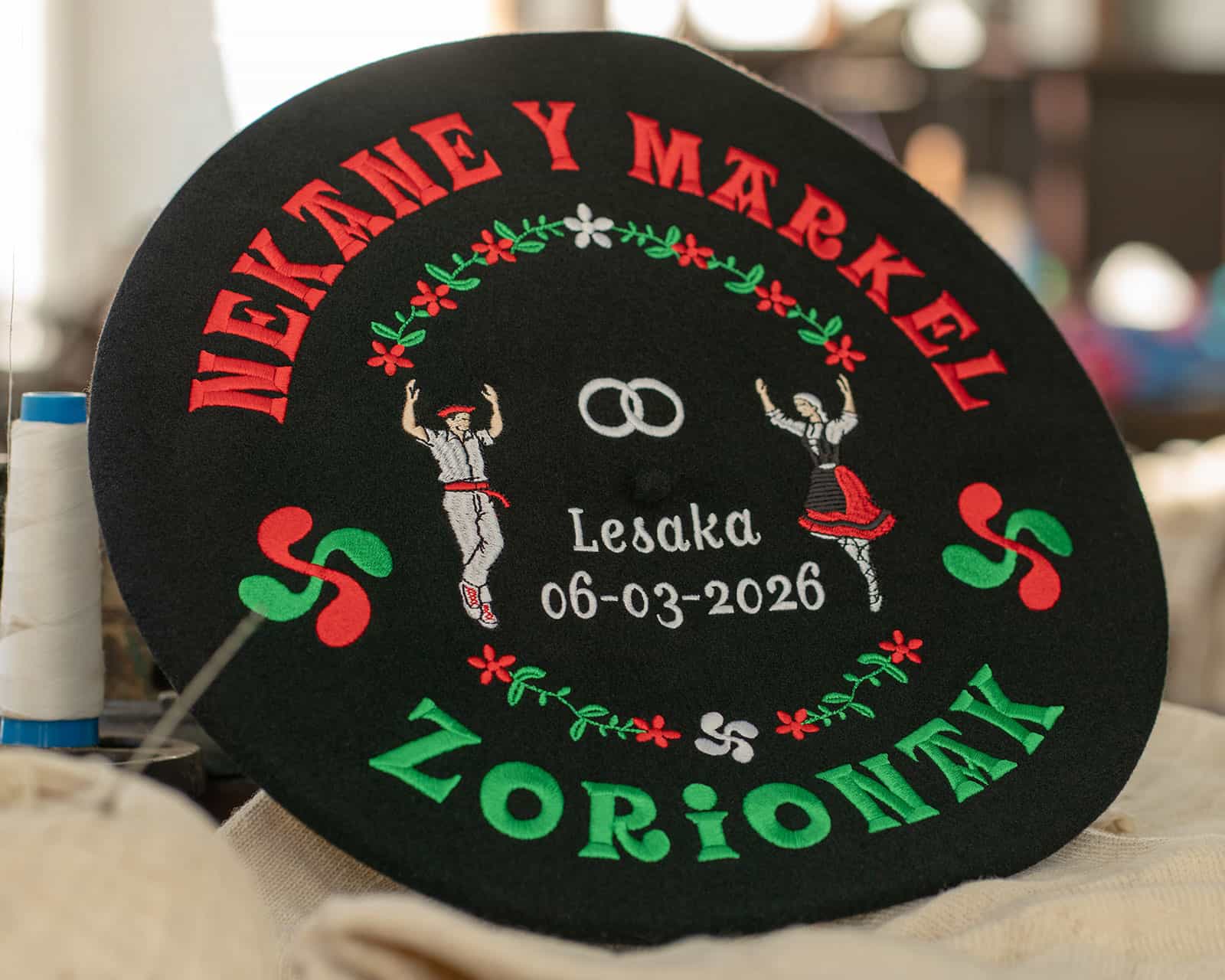 Txapela bordada bien hecha para boda con dantzaris, anillos, fecha 06-03-2026 en Lesaka y motivos florales, ejemplo de bordado de calidad de Teletxapela